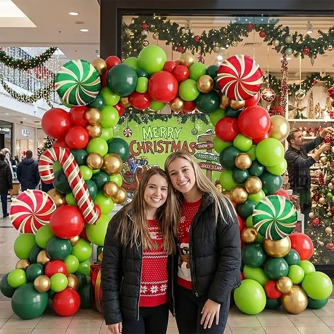 Christmas cartoon style party decorations include green red and gold balloon arch kit & candy canes lollipops gift boxes foil balloons & backdrop for Christmas New Year's Eve party decorations.